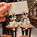 Close-up of elegant zirconia horseshoe earrings with clustered white artificial pearls. - 18# Drop