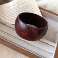 Gros plan détaillé d'un jonc en résine marron foncé vintage dans un plateau à bijoux beige chic. - Grain de Bois