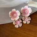 Primo piano di eleganti orecchini a lobo a fiore in smalto rosa e oro su un tavolo - Oro-Rosa