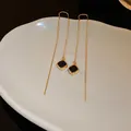 Detailansicht von Gold-Quastenohrringen mit schwarzem geometrischem Anhänger - Quadratischer Geometrischer Stil (HE7851) / Gold