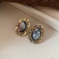 Close-up of vintage oval resin earrings with ornate gold-tone frames on textured background - Stud Earrings / Gold-Grey / Hypoallergenic Silver Earring Post