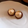 Close-up detail showing the gold woven texture and brown flocked border of retro earrings - Brown