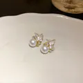 Dettaglio di orecchini a lobo farfalla con perla e strass su piatto di ceramica. - Stile Perla Farfalla / Perno in Argento-Oro-Bianco