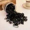 Detail view of black disposable hair bands spilling out of a transparent storage jar. - Wide Style / 450 Pieces/Pack (0.4cm) / Black