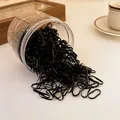 Close-up of disposable black elastic hair bands spilling from a clear container on a table - Fine Style / 450 Pieces Pack (0.2cm) / Black
