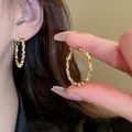 Macro view of golden oval hoop earrings featuring a unique geometric textured surface design - Geometric Faceted Oval Hoop Earrings (32) / Gold