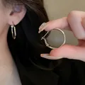Close-up of silver-toned oval hoop earrings with a secure clasp mechanism. - Oval Hoop Style (35) / Diameter 25mm / Silver