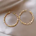 Detailed macro view of large golden hoop earrings featuring a faceted geometric texture. - Geometric Faceted Hoop Style (49#) / Gold