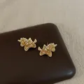 Close-up of gold plated unicorn stud earrings with sparkling amber zircon stones - Gold with Light Coffee