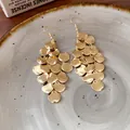 Detailed view of gold multi-layered hammered disc drop earrings on a ceramic plate. - Irregular Leaf Tassel Style / Ear Hook - Gold