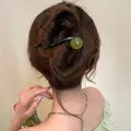 Detail view of a minimalist hair clip with a green resin bead in a bun hairstyle - 8-Shape Clip (HH5990) / Green