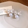 Detailed macro view of silver-toned wrinkled bow-knot earrings with elegant pearl pendants - Silver
