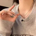 Schicke silberne Schichtkette mit schwarzem Herzanhänger auf grauem Sweatshirt. - Schwarz