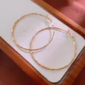 Detailed view of large gold textured hoop earrings on a minimalist wooden display tray. - Hammered Hoop (HE8275) / 59mm / Gold