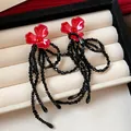 Close-up of red flower stud earrings with long black beaded tassels on jewelry tray - Silver Needle Flower Tassel Style / Red-Black