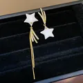 Detailed macro view of asymmetric star earrings featuring 18k gold plating and shiny zircon - Asymmetrical Star Tassel (WE6050) / Gold with White
