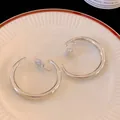 Dettaglio orecchini a clip argento a forma di C su piatto di ceramica bianca - Orecchini a clip / Argento