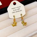 Detail shot of golden horse stud earrings with red copper coin charms on a card. - Galloping Horse Style (9#) / Gold-Red