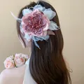 Detaillierte Nahaufnahme einer eleganten Stoffblumen-Haarklammer auf braunem Haar - Lila Blumen Feder (25#)