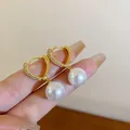 Nahaufnahme eleganter goldener herzförmiger Creolen mit hängenden runden weißen Perlen - Heart Ear Clip Style (5#) / Gold
