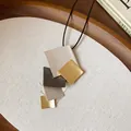 Macro view of a minimalist multi-layered geometric metal pendant necklace on a black cord - Gold, Silver, Gray