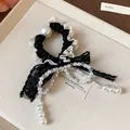 Close-up of elegant French lace bow hair tie with pearl bead tassels for women - Black