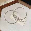Large silver hoop earrings with a diamond-cut textured finish in a wooden tray. - 6cm / Facet Craftsmanship / Silver