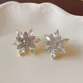 Close-up of crystal snowflake earrings with intricate rhinestone details on a cream plate. - Silver Post Golden Crystal Snowflake (27#)