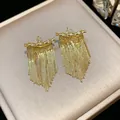 Gros plan de boucles d'oreilles à pampilles dorées avec zircon et franges de chaînes - Or
