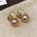 Gros plan détaillé de boucles d'oreilles cœur en or de style français avec perles champagne - Style de Crochet / Or avec Café