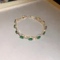 Close-up of a vintage court style gold bracelet with emerald green stones - Gold