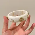 Dettaglio bracciale rigido in resina marmorizzata con inserti a conchiglia dorata e perle. - Stile 27 (WB1456WB1187)