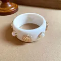 Dettaglio di un bracciale rigido in resina bianca con conchiglie dorate e accenti di perle - Stile 31 (WB1456WB1187)