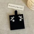 Close-up detail showing sparkling zircon bow and star stud earrings on a display stand. - Silver Earring Post Style / Silver