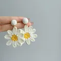 Detail view of handmade woven daisy drop earrings with white petals and yellow center. - 5# Steel Post - Off-White - Yellow