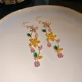 Macro view of glittering zircon butterfly and flower tassel earrings in gold - Butterfly Flower Tassel Style / Colorful