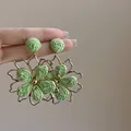 Close-up of green woven flower earrings with gold metal frame detailing. - 3# Sterling Silver Pin-Gold-Green