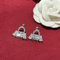 Close-up of sparkling handbag-shaped stud earrings with clear crystals on red background. - Handbag Style (HE28616-) / Silver