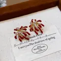 Macro detail of firework stud earrings with red enamel and brilliant zircon stones - Earrings / Gold-Red (Gold Plated)