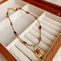 Vue détaillée du collier vintage en perles d'œil de tigre avec pendentif goutte d'or - Style Ovale Irrégulier