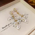 Detailed view of elegant gold-toned earrings with pearls, zircons and flower petals. - Flower Style / Cream White