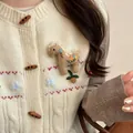 Dettaglio di una graziosa spilla poney in tessuto ricamato su un cardigan bianco - Caffè - Stile fiore