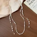 Elegant detail of a French style long pearl necklace with teardrop crystal pendants. - Necklace / White