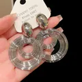 Dettaglio degli orecchini a cerchio in metallo argentato con cerchi concentrici. - Tondo Avvolto / Argento