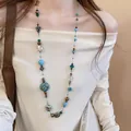 Detailed close-up of a bohemian retro necklace with colorful irregular glass beads on a model. - 5# Necklace - Gold & Blue