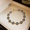 Dettaglio di elegante bracciale regolabile in perle grigie e oro in scatola regalo - Cordoncino regolabile / Perla Grigia / Oro