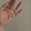Vintage gold plated necklace featuring a round tiger eye stone pendant, elegantly held in hand - 20# Necklace - Gold - Coffee