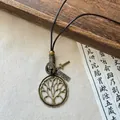 Close-up of vintage Tree of Life pendant necklace with bronze finish on wooden surface - Gold-Coffee-Round