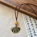 Detail view of Zen style ginkgo leaf pendant necklace with wooden bead and brown cord - Gold-Brown-Leaf