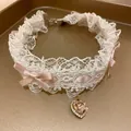 Vista dettagliata di un elegante choker in pizzo bianco con fiocchi rosa e ciondolo a cuore - Rosa